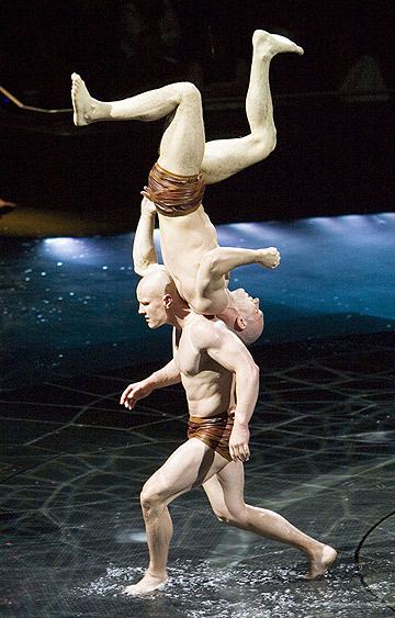 two male acrobats performing incredible balancing act on the pool