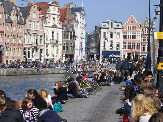 students along the banks of the River Leie on the first warm day of Spring in Ghent