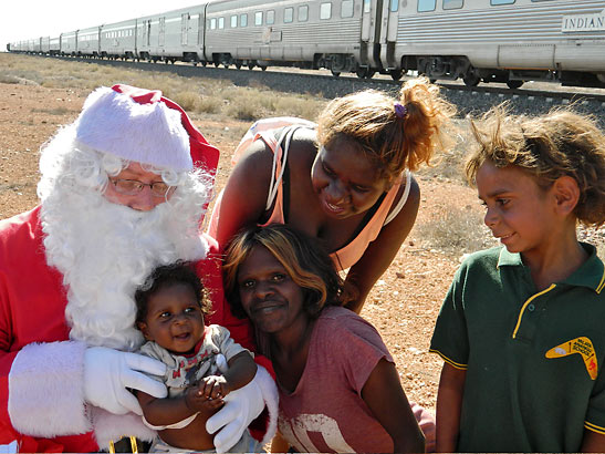 Indian Pacific train's Santa with child at a remote stop near an indigenous settlement