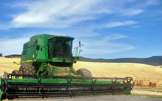 green combine harvesting wheat on the rolling hills of the Palouse, eastern Washington
