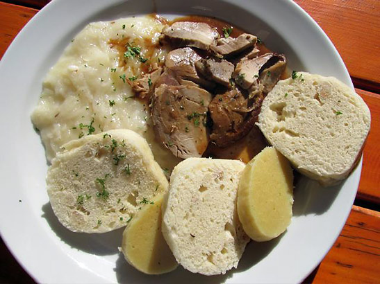 a dish of pork, mashed sauerkraut, dumplings and potatoes