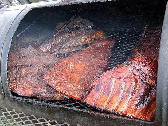 barbecued ribs and other slices of beef on a grill