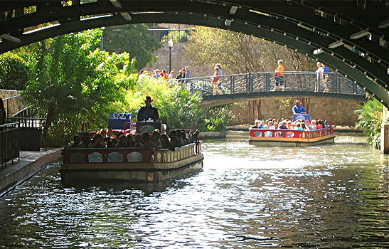 boats loaded with visitors sailing on canal, San Antonio River Walk