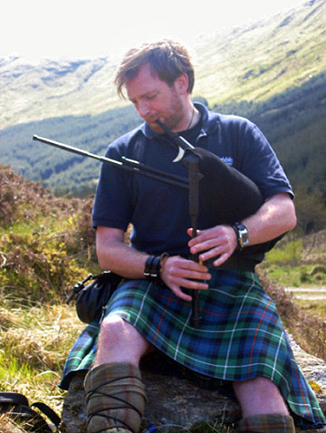 Scot in traditional attire playing a bagpipe