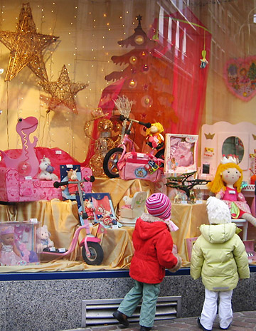 children in colorful garb examining display at a toy store, Geneva