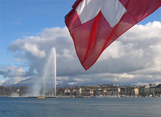 the Jet d'Eau - a large fountain in Lake Geneva with the Swiss flag in the foreground