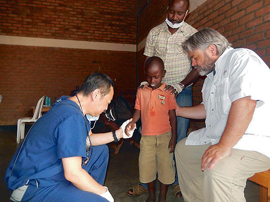 Dr. Lee in prayer with a Rwandan boy
