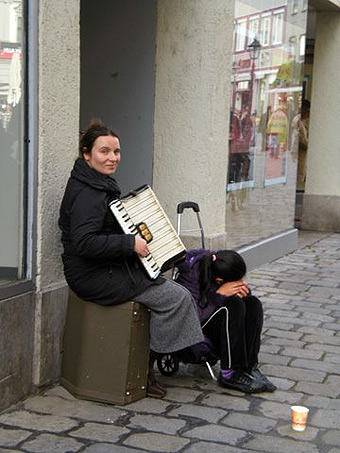woman playing accordion with child on street