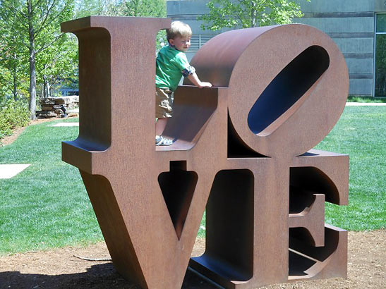 child playing on a sculpture at the park around the Crystal Bridges Museum of American Art
