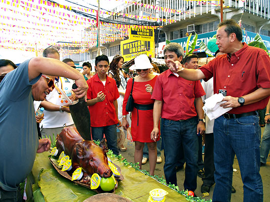 Iligan Rep. Belmonte and Mayor Cruz watching a roasted pig being chopped uo for a contest on Pagpakanaug Day