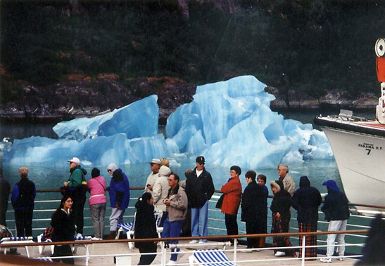 tourists on a deck of a cruise ship passing an ice floe in the background