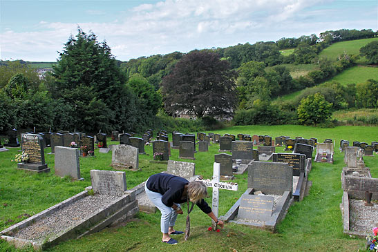 a simple white cross signifies Dylan Thomas' final resting place in Laugharne's cemetery