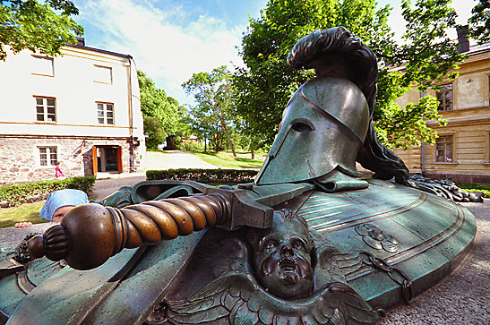 little girl looking at grave of Augustin Ehrensvard with Greek hoplite helmet, Helsinki