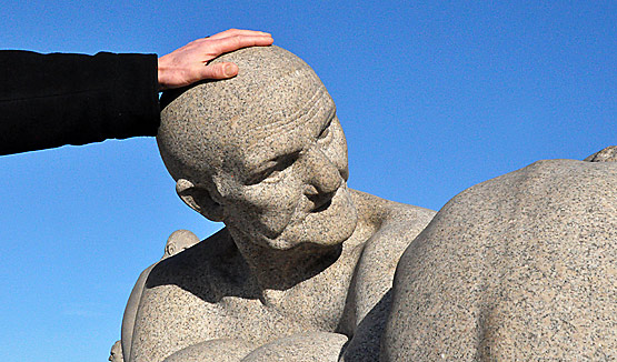 visitor rubbing the head of a sculpture at Vigeland Sculpture Park
