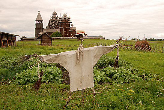 scarecrow in field with wooden church in background, Kizhi Island, Russia