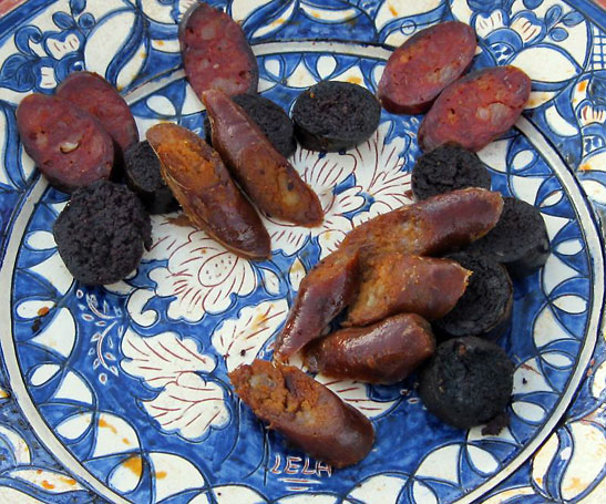 a collection of various cured meat on a classically decorated Portugese platter