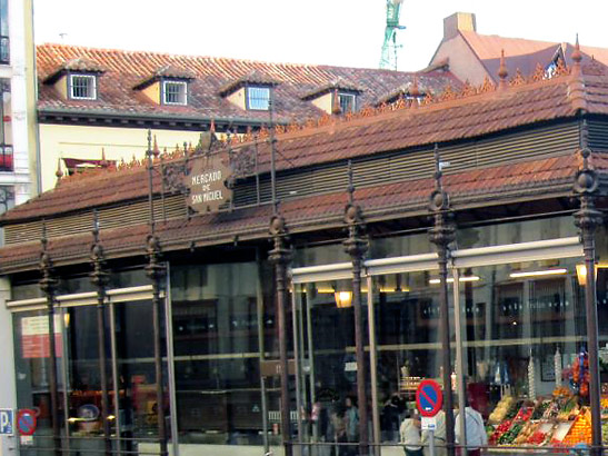 the iron and glass facade of the Mercado de San Miguel, a collection of tapas stalls and bars converted from a neighborhood market, Madrid