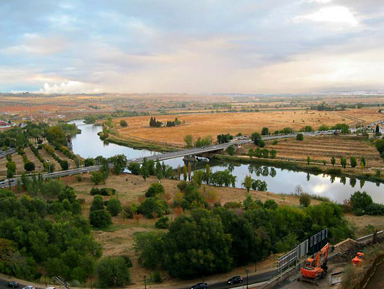 view of plains below the hilltop city center where new escalator will land with on-going construction in the right foreground