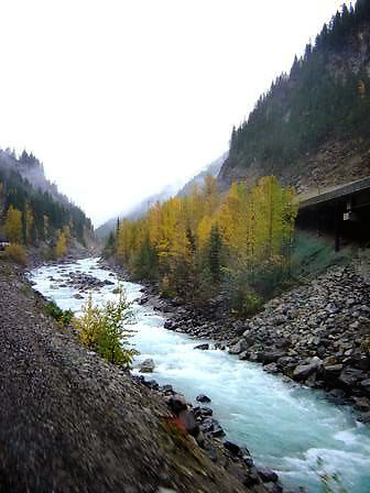 view of stream by a hillside from inside Rocky Mountaineer train