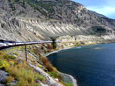scenic picture of lake and hillside taken from inside a Rocky Mountaineer train