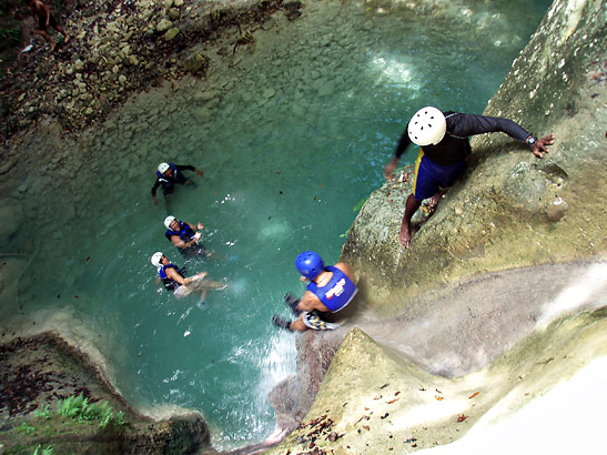 tourists in helmets and life jackets jumping over a waterfall into a pool - part of the waterfall escapade of Iguana Mama at Puerto Plata