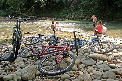 bikers taking a relaxing dip at a pool at an Iguana Mama mountain bike adventure