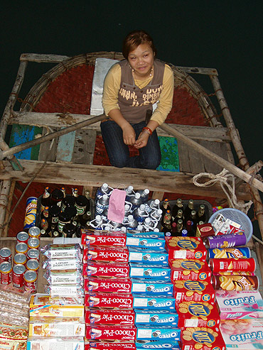 a vendor sells items on board a boat, Halong Bay