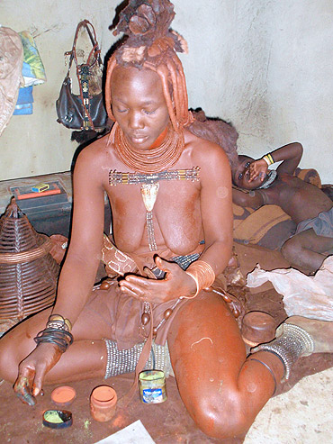 Himba woman covering body with red ocher pigment, Namibia