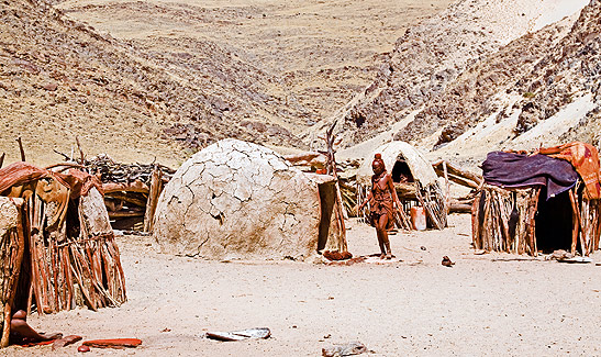 woman amidst circular huts in a Himba village