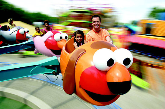 children with parents at a kiddie ride in a theme park