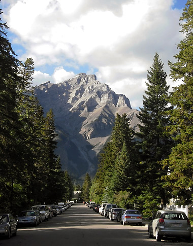 tree-lined road inside Banff with mountain peak in the background