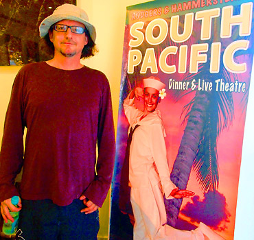 the writer beside an ad for a South Pacific Dinner & Live Theater at the Kauai Beach Resort