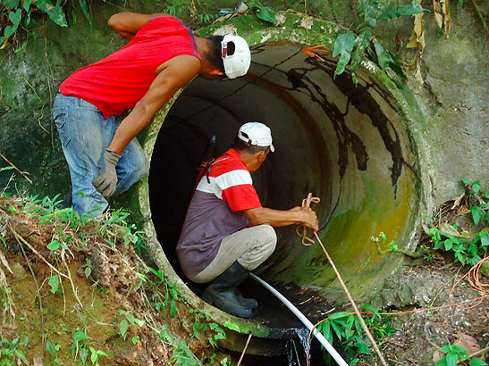 workers running aqueduct line through a tunnel underneath a road
