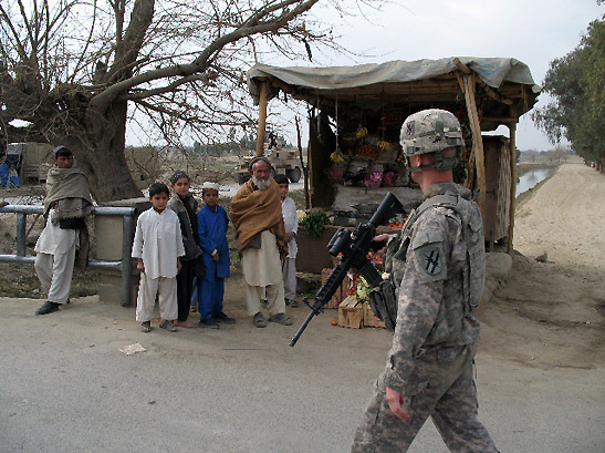 American soldier passing by fruit stall with local children and elderly man