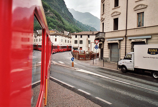 a Bernina Express train gliding down a street in the town of Tirano, Italy