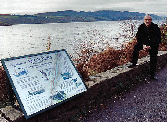writer standing by a sign at Loch Ness that tells the story of an RAF bomber that went down in the lake