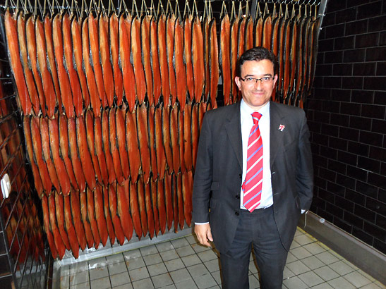 Lance Forman standing in front of rows of dried salmon at his factory