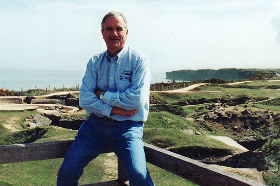 the writer at Pointe du Hoc with crater-filled landscape in the background