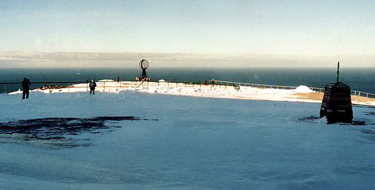 a field of snow with the sea in the background