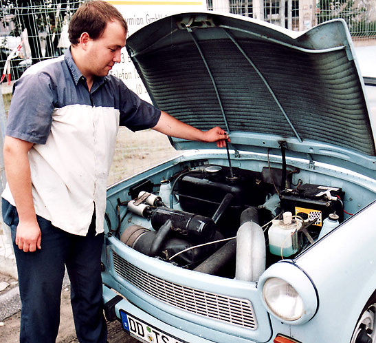 person checking the oil of a Trabant car, Germany