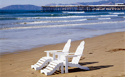 two beach chairs on beach with Pismo Beach Pier in the background