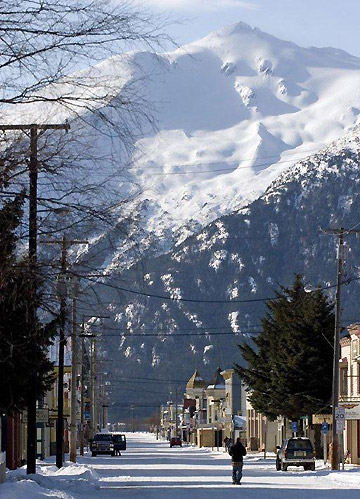 a street in Skagway, Alaska with the snow-capped mountains of the Alaskan Range in the background
