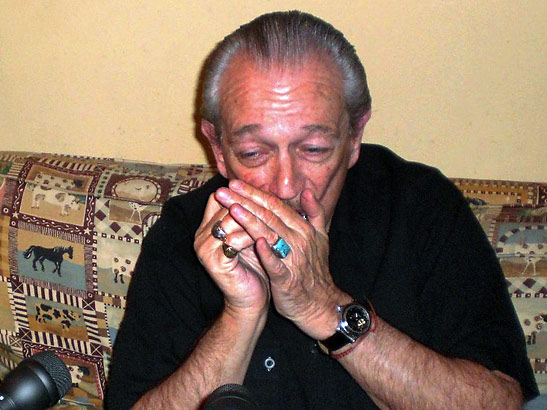 Charlie Musselwhite playing a harmonica backstage