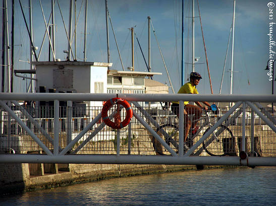 biker crossing a small bridge to a breakwater at the port of Senigallia