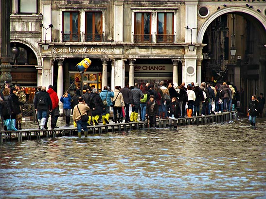 crossing a Venice street during aqua alta on a temporary walkway
