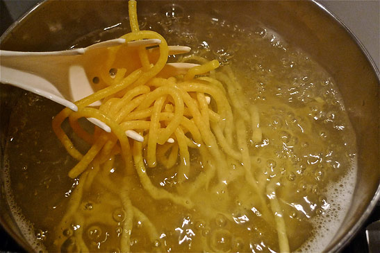 bigoli pasta cooking in a pot of boiling water